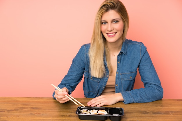 Mujer rubia joven que come el sushi