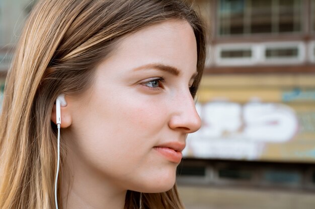 Mujer rubia joven que escucha la música con los auriculares