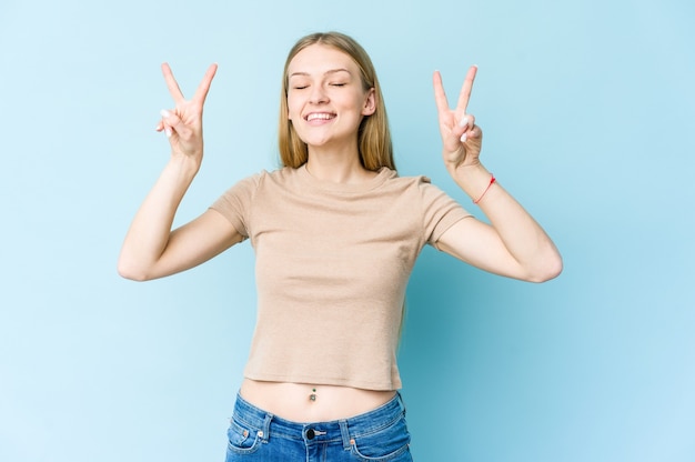 Mujer rubia joven que muestra el signo de la victoria y una amplia sonrisa.