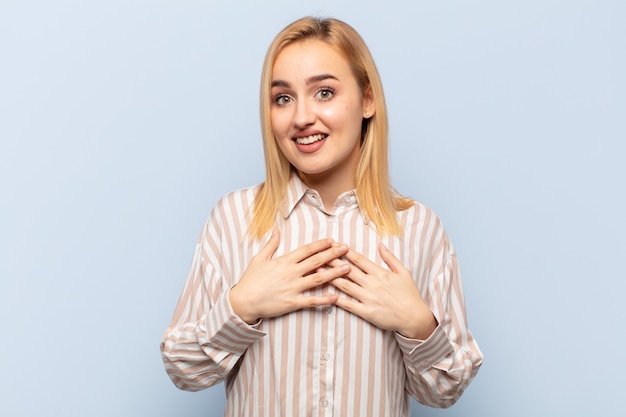 Mujer rubia joven que parece feliz, sorprendida, orgullosa y emocionada