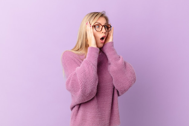 Mujer rubia joven que se siente feliz, emocionada y sorprendida