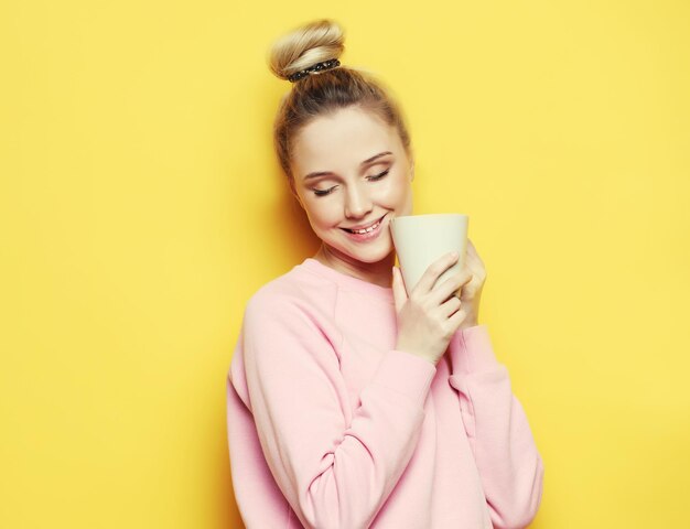 Mujer rubia joven sosteniendo una taza blanca con estilo de vida de té o café y concepto de comida