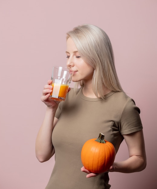 Mujer rubia con jugo de calabaza en rosa