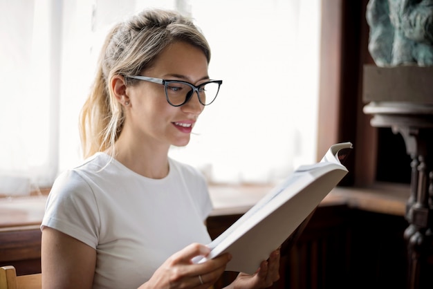 Mujer rubia leyendo un libro en la biblioteca