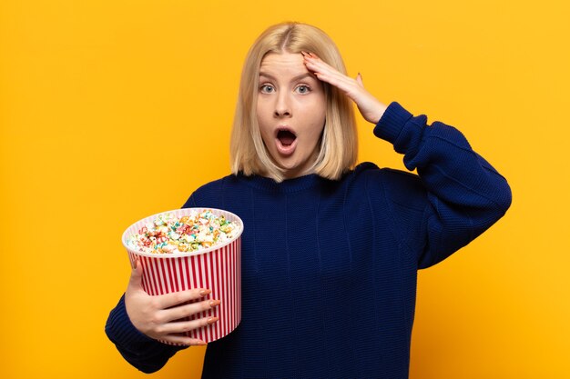 Mujer rubia luciendo feliz, asombrada y sorprendida, sonriendo y dándose cuenta de buenas noticias increíbles e increíbles