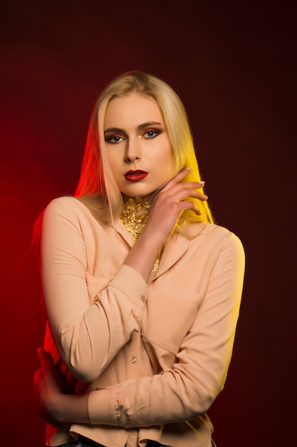 Mujer rubia de lujo con maquillaje brillante. Luz de estudio roja y amarilla