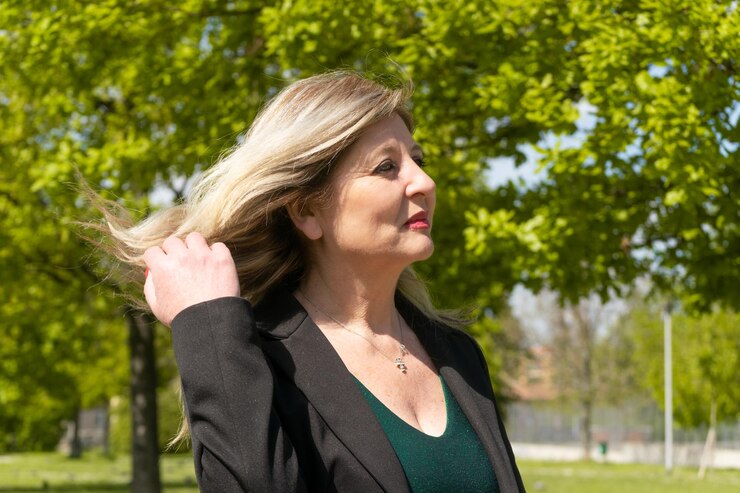 Mujer rubia madura feliz posando en el parque