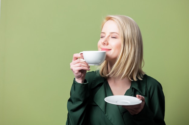 Mujer rubia en manto con taza de café