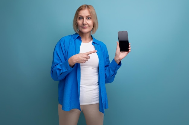 Foto mujer rubia de mediana edad con corte de pelo bob sosteniendo teléfono inteligente con mocap en el fondo del estudio