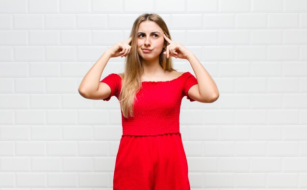 Mujer rubia mirando concentrada y pensando mucho en una idea, imaginando una solución a un desafío o problema