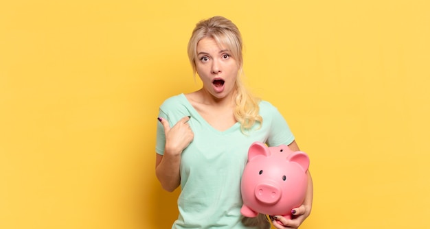 Mujer rubia mirando consternado y sorprendido con la boca abierta