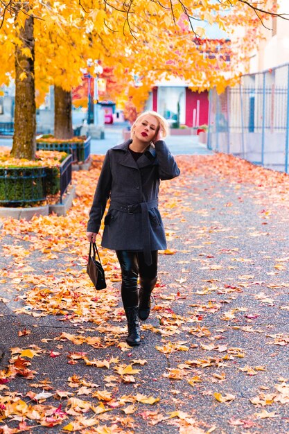 Mujer rubia de moda caminando explorando la ciudad