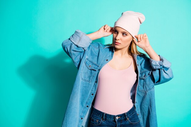 Mujer rubia de moda posando contra la pared azul