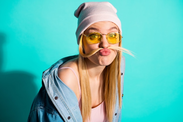 Mujer rubia de moda posando contra la pared azul