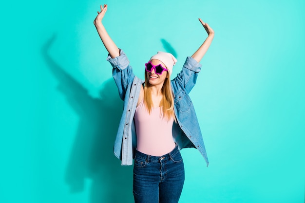 Mujer rubia de moda posando contra la pared azul