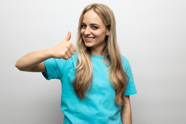 Mujer rubia mostrando clase con el dedo sobre fondo blanco.