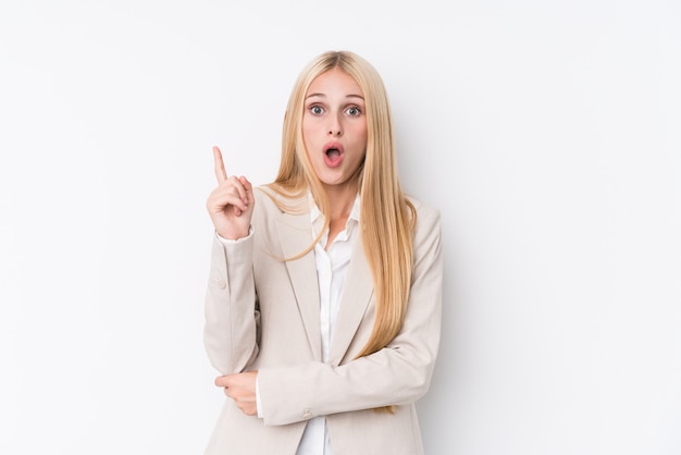 Mujer rubia del negocio joven en la pared blanca que tiene una gran idea, concepto de creatividad.