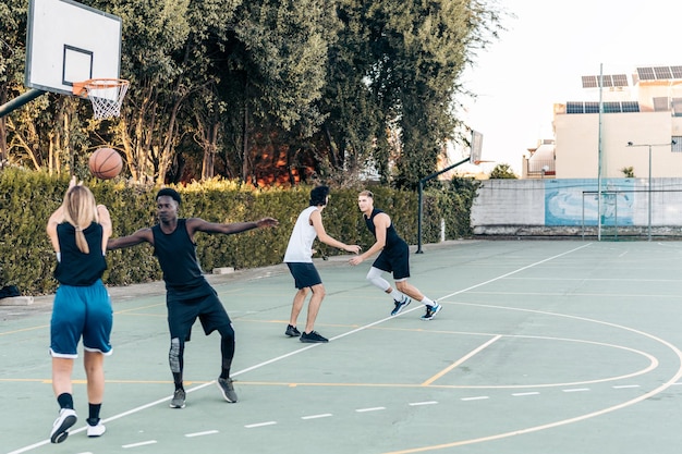 Mujer rubia pasando la pelota durante un partido de baloncesto entre amigos en una cancha pública abierta