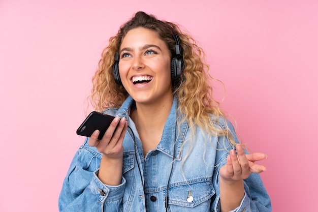 Mujer rubia con pelo rizado aislado escuchando música