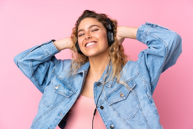 Mujer rubia con pelo rizado aislado escuchando música