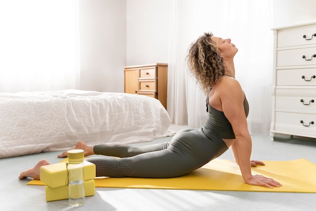 Foto mujer rubia de pelo rizado haciendo yoga en casa