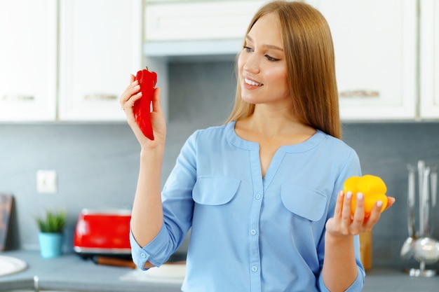 Foto mujer rubia de pie en la cocina y cocinar