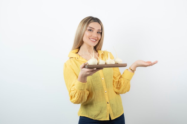 Mujer rubia con plato de nabos blancos posando sobre blanco