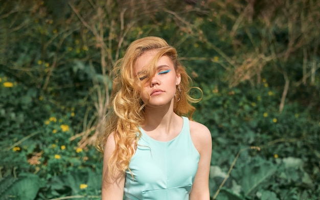 Una mujer rubia posando en la naturaleza.