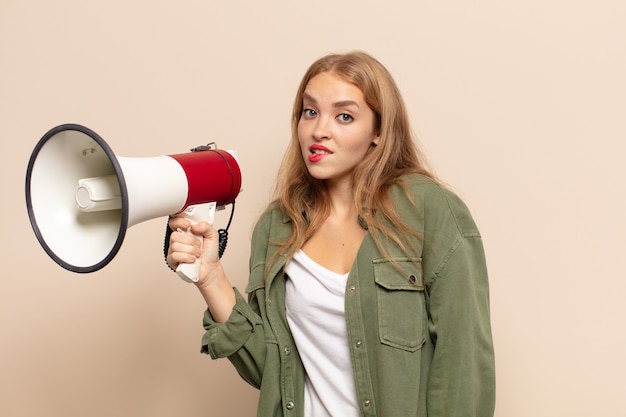 Mujer rubia que mira perpleja y confundida, mordiendo el labio con un gesto nervioso