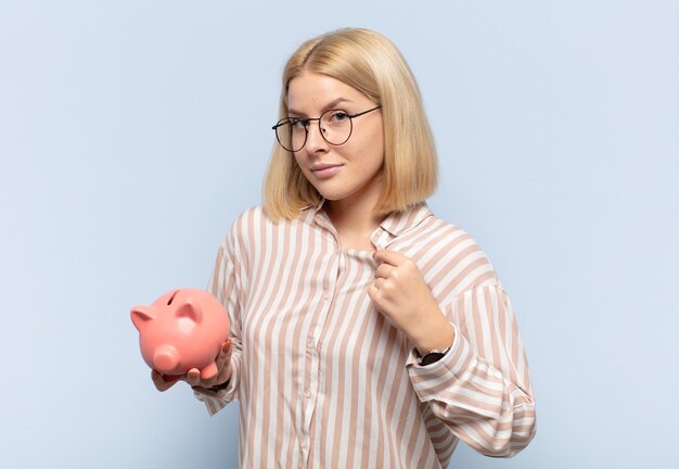 Mujer rubia que parece arrogante, exitosa, positiva y orgullosa, apuntando a sí misma