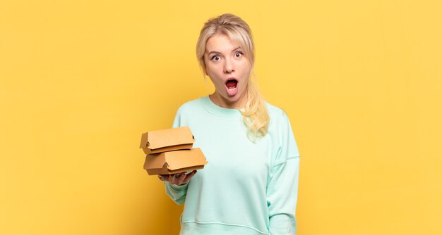 Mujer rubia que parece muy conmocionada o sorprendida, mirando con la boca abierta y diciendo wow