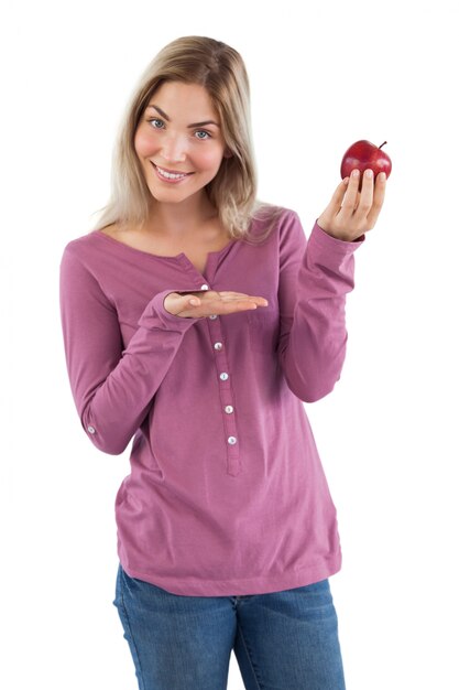 Mujer rubia que presenta una manzana