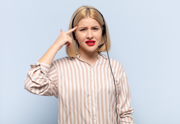 Mujer rubia que se siente confundida y perpleja, mostrando que estás loco, loco o loco