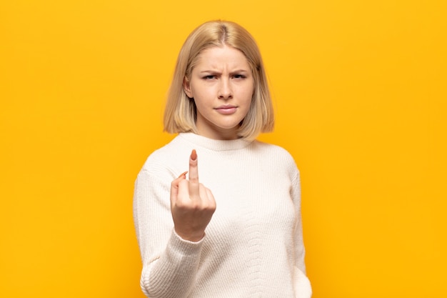 Mujer rubia que se siente enojada, molesta, rebelde y agresiva, moviendo el dedo medio, luchando