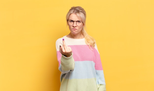 Mujer rubia que se siente enojada, molesta, rebelde y agresiva, moviendo el dedo medio, luchando