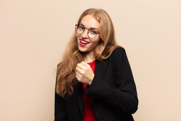 Mujer rubia que se siente feliz, positiva y exitosa, motivada al enfrentar un desafío o celebrar buenos resultados.