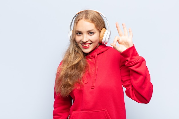 Mujer rubia que se siente feliz, relajada y satisfecha, mostrando aprobación con gesto bien, sonriendo