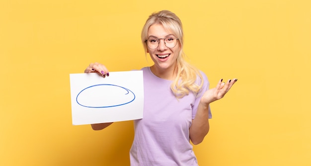 Mujer rubia que se siente feliz, sorprendida y alegre, sonriendo con actitud positiva, dándose cuenta de una solución o idea