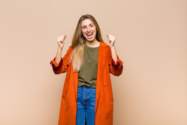 Mujer rubia que se siente sorprendida, emocionada y feliz, riendo y celebrando el éxito, diciendo ¡guau!