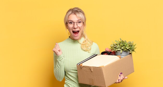 Mujer rubia que se siente sorprendida, emocionada y feliz, riendo y celebrando el éxito, diciendo ¡guau!