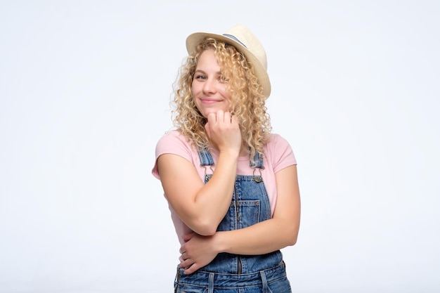 Mujer rubia rizada joven que parece confiada con una sonrisa en la cámara