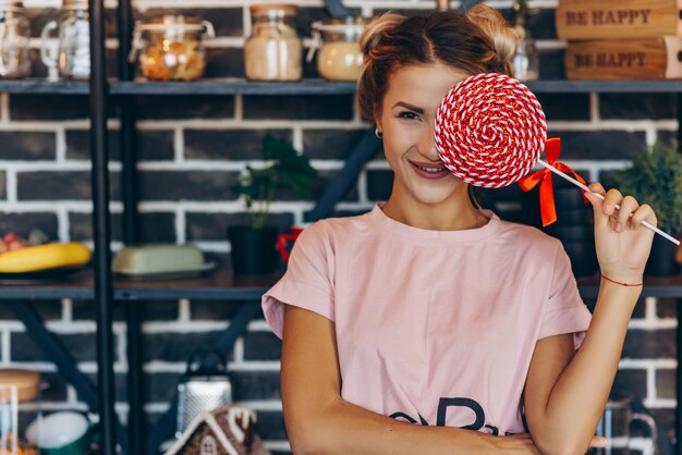 Mujer rubia en rosa con una gran piruleta en las manos.