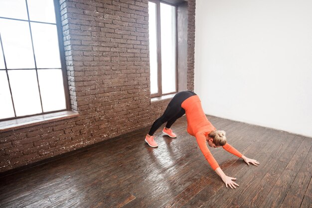 Mujer rubia sexy haciendo asana cerca de la pared de ladrillo