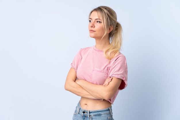 Mujer rubia sobre azul aislado mirando hacia el lado