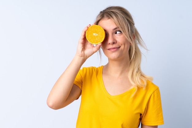 Mujer rubia sobre azul aislado sosteniendo una naranja