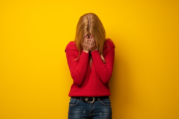 Mujer rubia sobre pared amarilla con expresión cansada y enferma