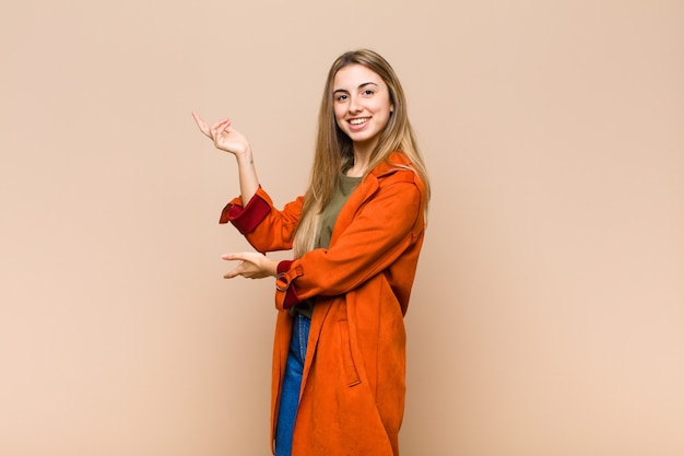 Mujer rubia sonriendo con orgullo y confianza, sintiéndose feliz y satisfecha y mostrando un concepto en el espacio de la copia