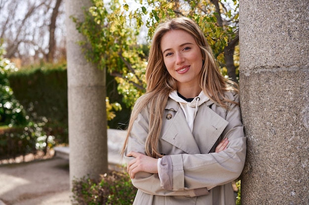 Mujer rubia sonriendo en el parque disfrutando de un descanso mental