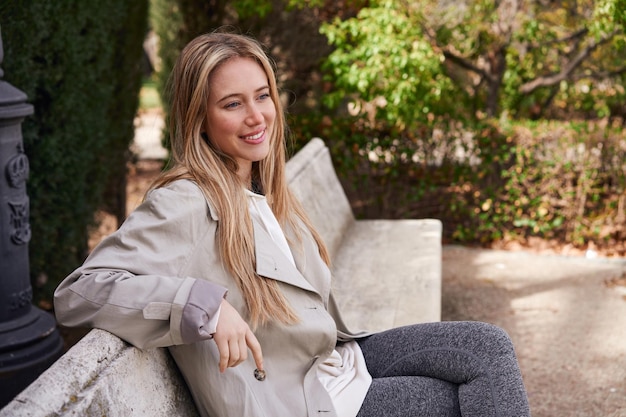 Mujer rubia sonriendo en el parque disfrutando de un descanso mental