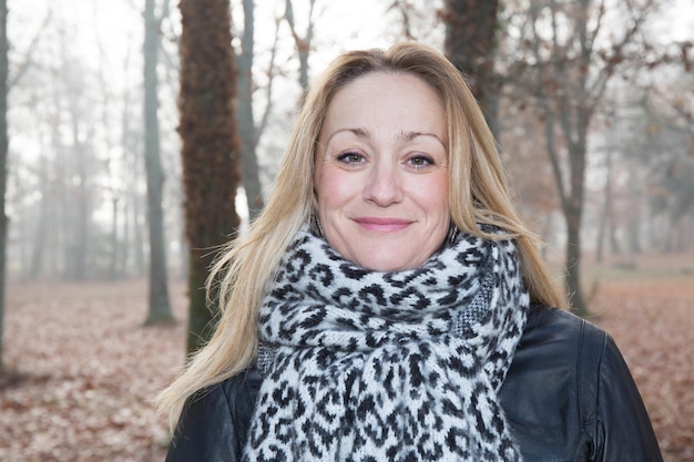 Mujer rubia sonriendo con el pelo largo en un parque inviernos